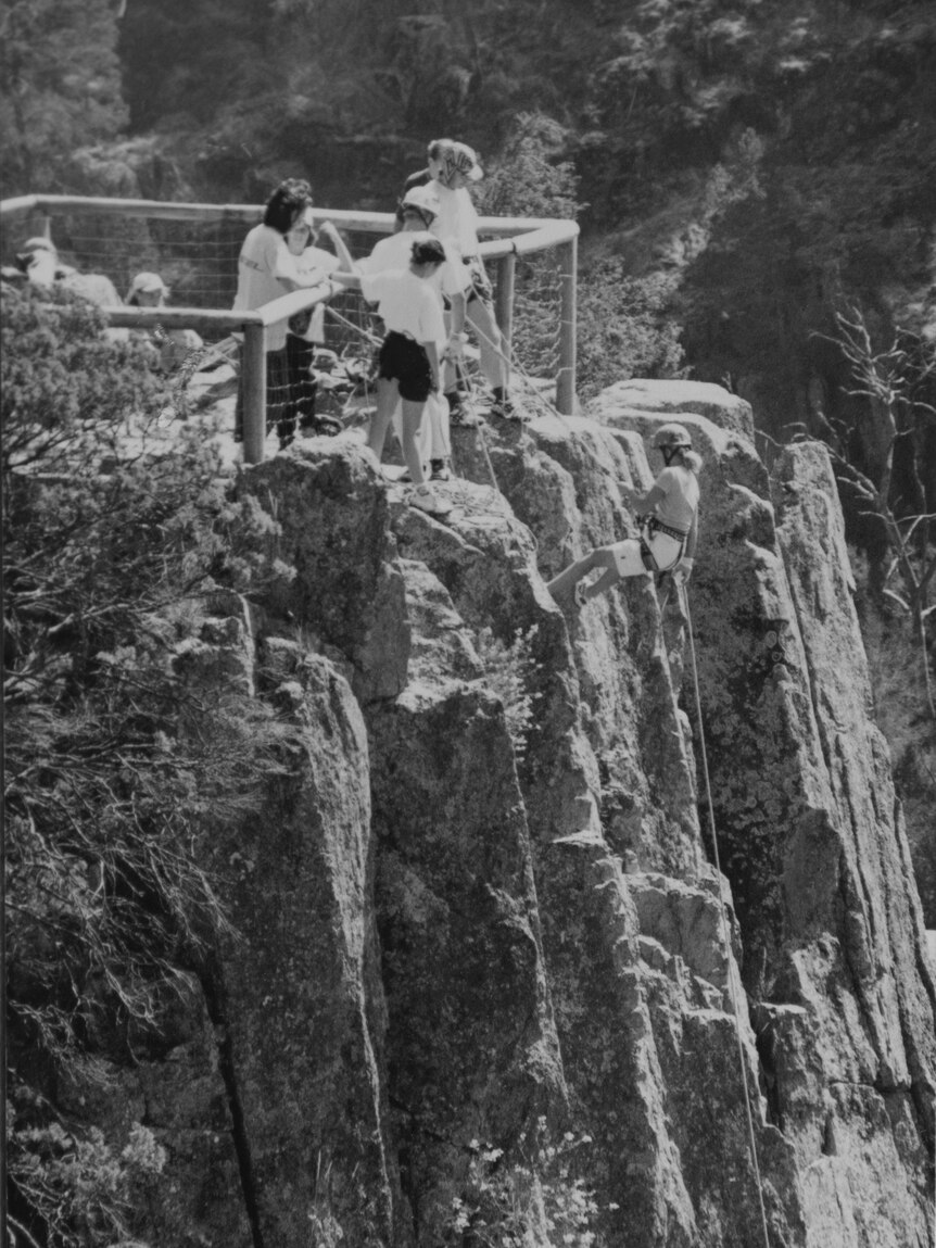 An old black-and-white photo showing a group of people at the top of a cliff.