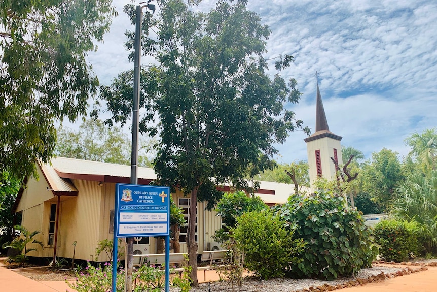 An outside view of a church surrounded by signage and trees