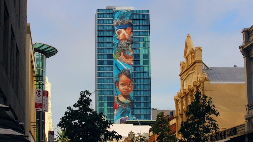 A huge mural stretches down the side of a 25 storey building