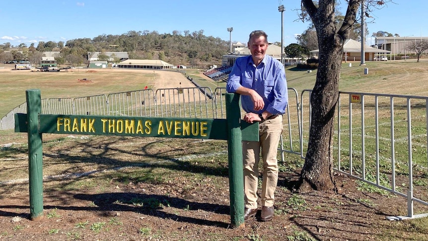 A man stands behind a sign that reads Frank Thomas Avenue