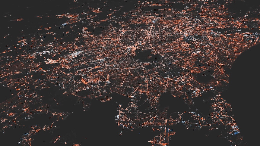 A country seen from far above - transport networks and cities are lit up against the dark