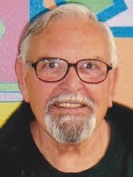 Arthur Greer in front of a colourful background.