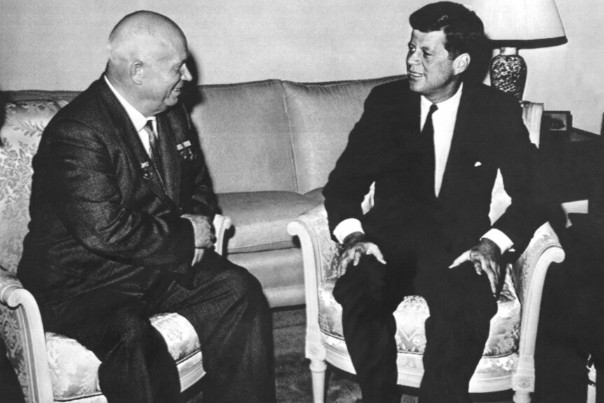 Black and white photo of Soviet Premier Nikita Khrushchev sits with US President John F. Kennedy.
