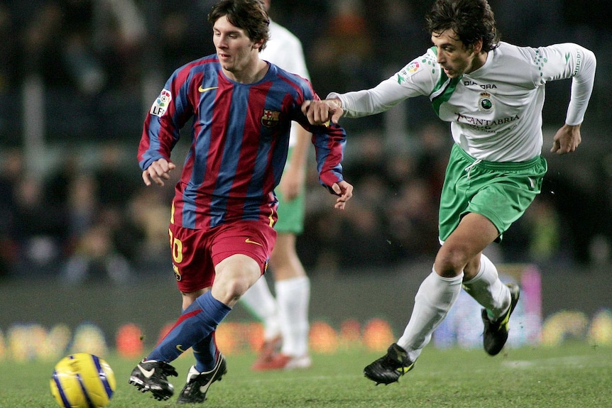 Lionel Messi fights for the ball with Racing Santander's Francisco Borja Neru during their league match at Nou Camp stadium