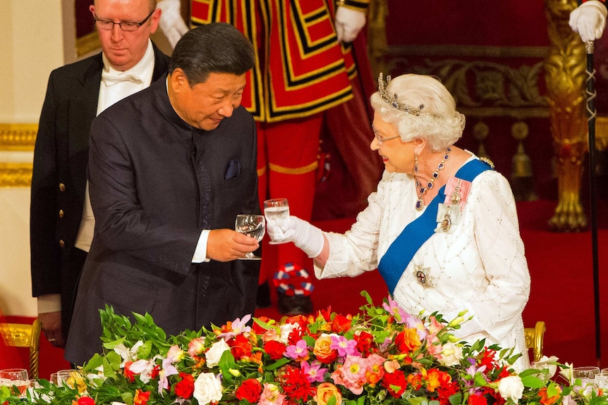 The Queen toasting her wine glass to Xi Jinping in a dining room