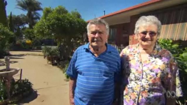 Elderly couple stand outside their house