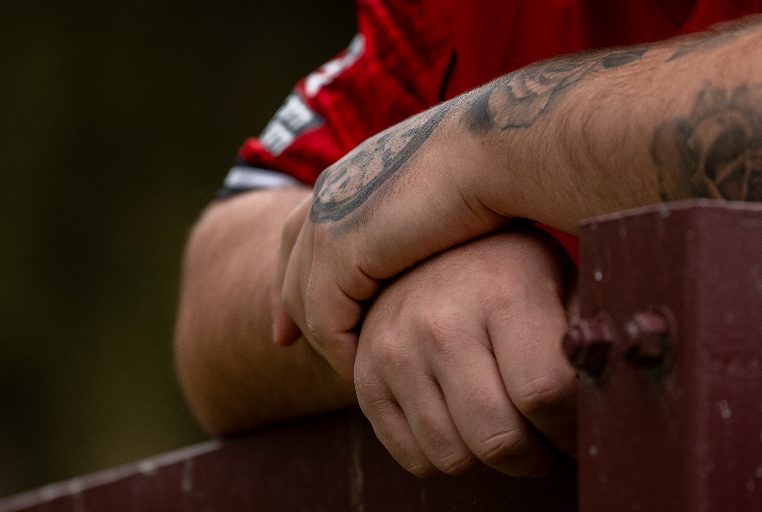 Um close das mãos de um homem com algumas tatuagens visíveis nas mãos e no braço.