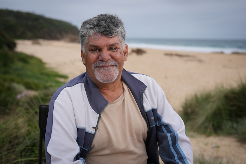 A man sitting in front of a beach. 