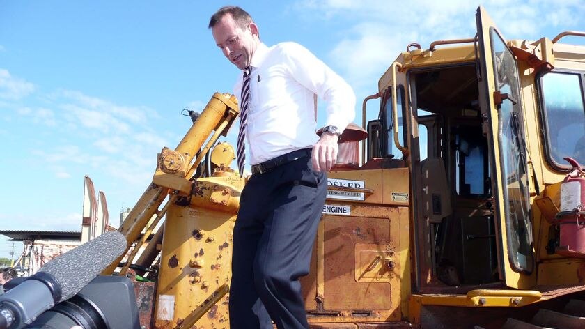 Tony Abbott gets down from a bulldozer while campaigning in Gladstone