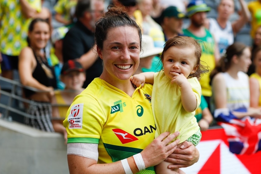 Emilee Cherry holds her toddler daughter Alice after playing a game of rugby union for Australia.