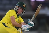 Beth Mooney paddles a ball down the leg side wearing the yellow Australian T20 uniform.