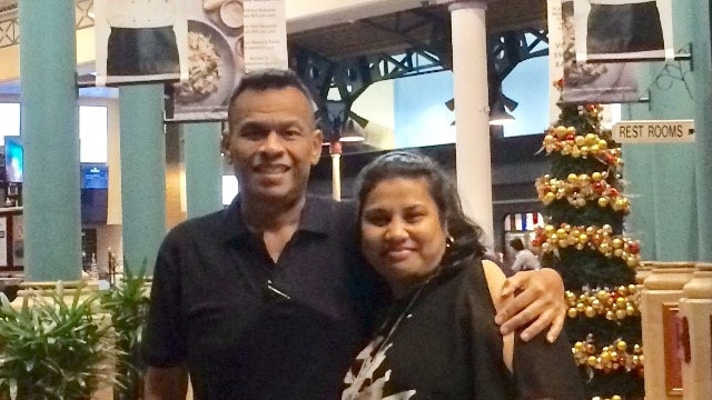 Sprent Dabwido is pictured standing with his arm around his wife Linda Dabwido in a food court.
