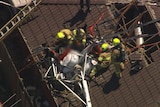 Emergency workers attend a helicopter crash into a roof.