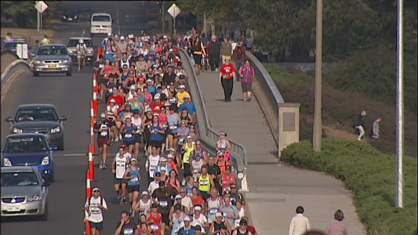 A large crowd of runners cross the Kings Avenue bridge for the Canberra Marathon route around the parliamentary triangle.