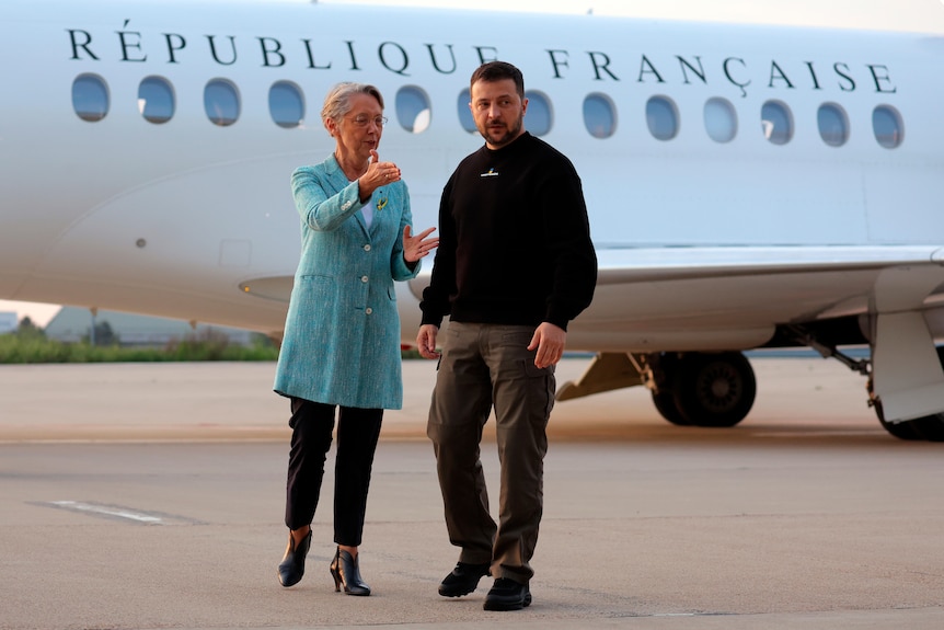 French Prime Minister Elisabeth Borne standing next to Ukrainian President Volodymyr Zelenskyy in front of a French plane.