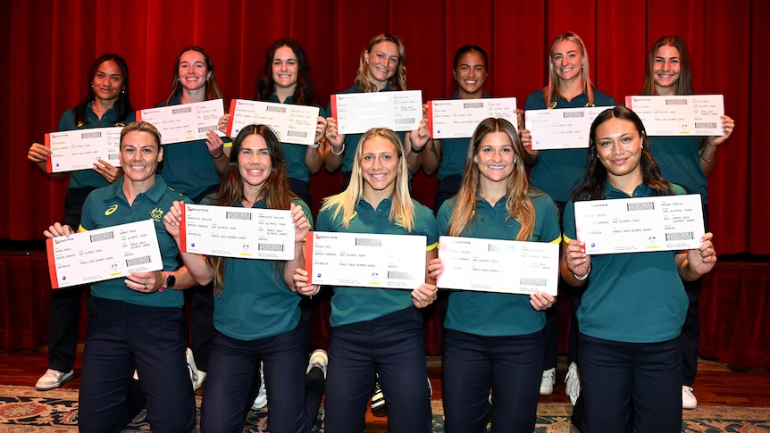 Members of the Australian women's rugby sevens team pose for a photo holding large boarding passes.