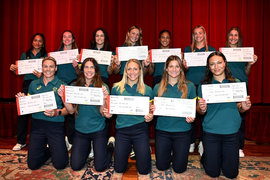 Members of the Australian women's rugby sevens team pose for a photo holding large boarding passes.