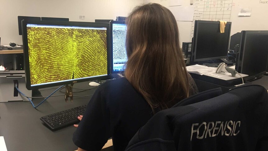 A woman looks at magnified fingerprints on a computer screen