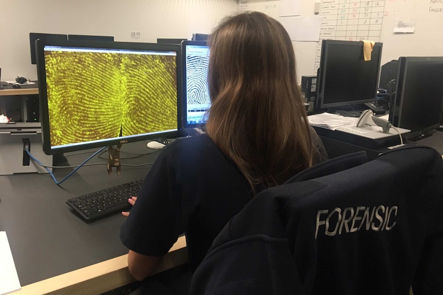 A woman looks at magnified fingerprints on a computer screen