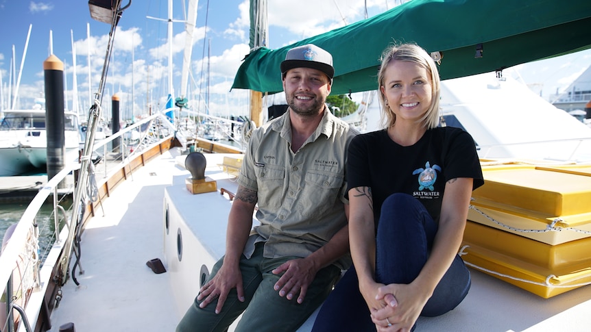 A man and woman sit side by side aboard a tall ship.