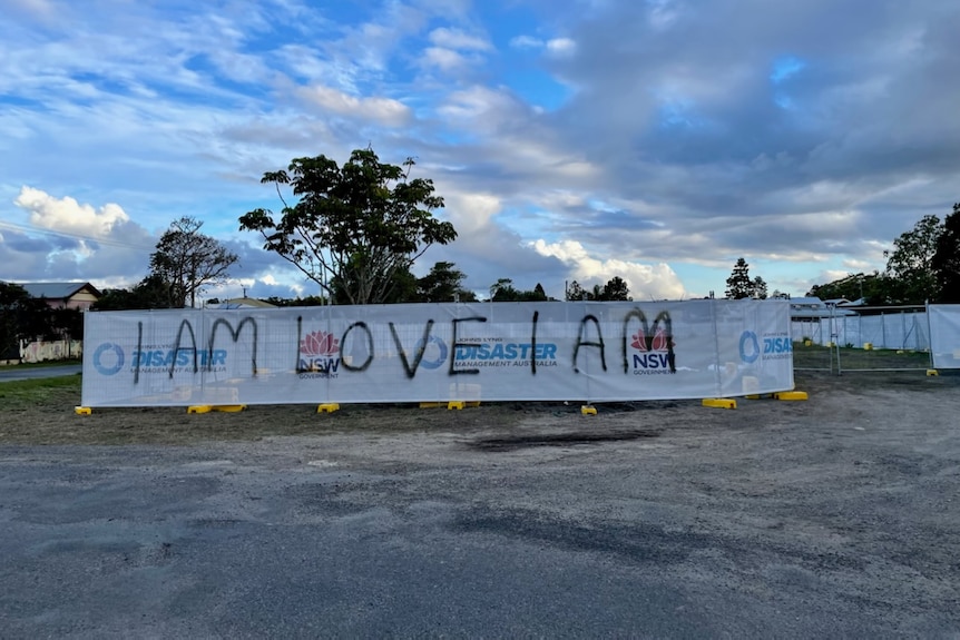 A sign reading "I am love I am" wrapped around a construction site.