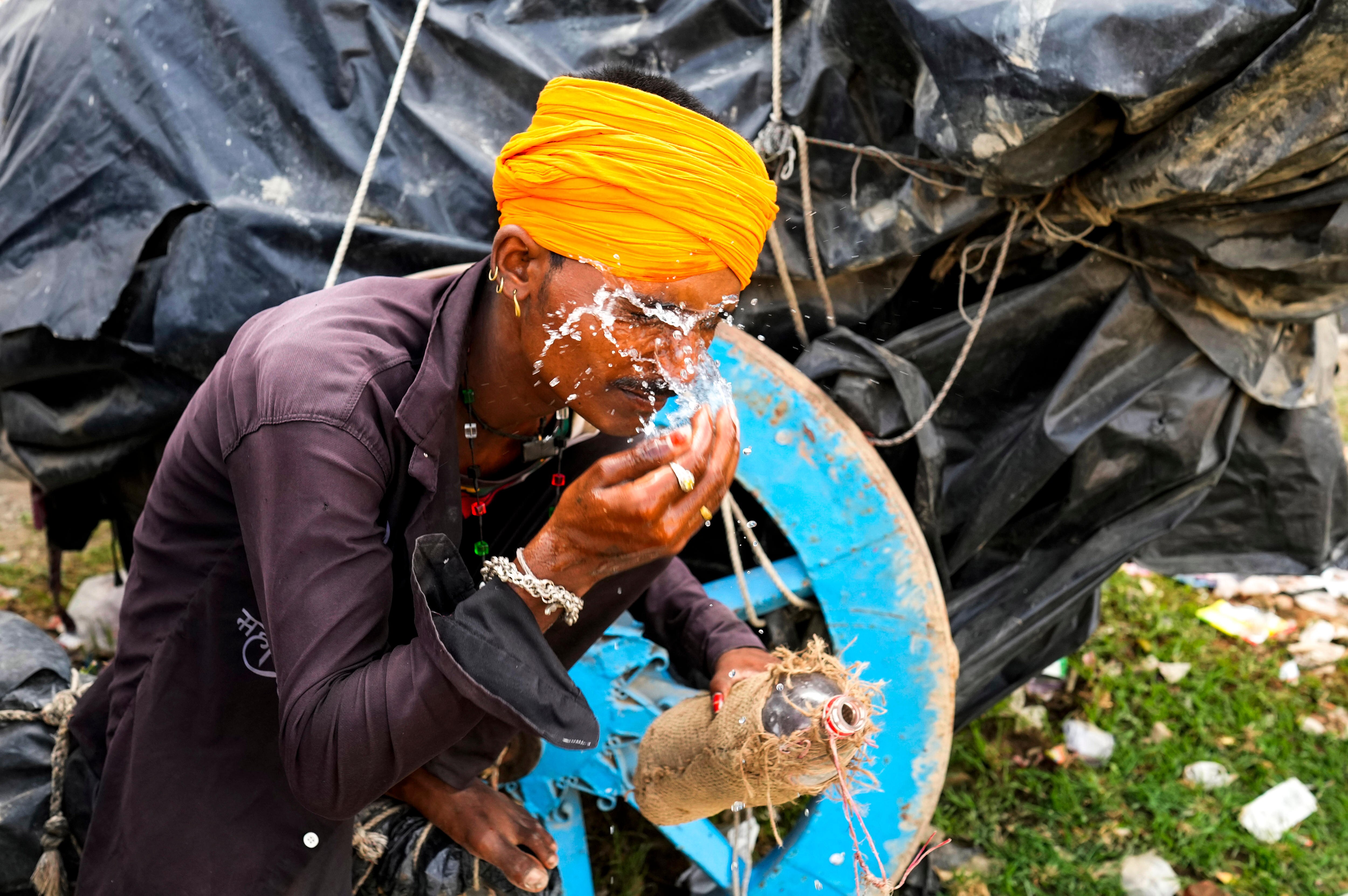 A man splashes water on his face to cool himself.