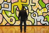 A man stands in front of a colourful graffiti-style artwork in the Chicago Cultural Centre.