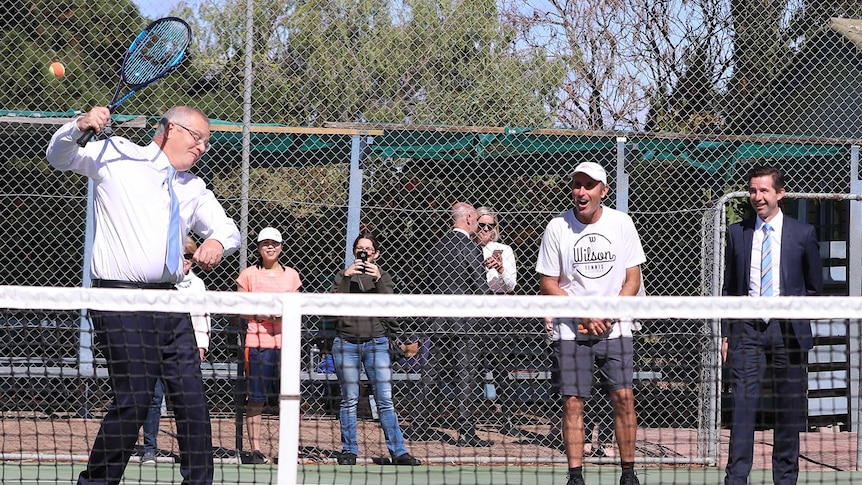 Mr Morrison pulls a face as he misses a ball. People watching on are laughing