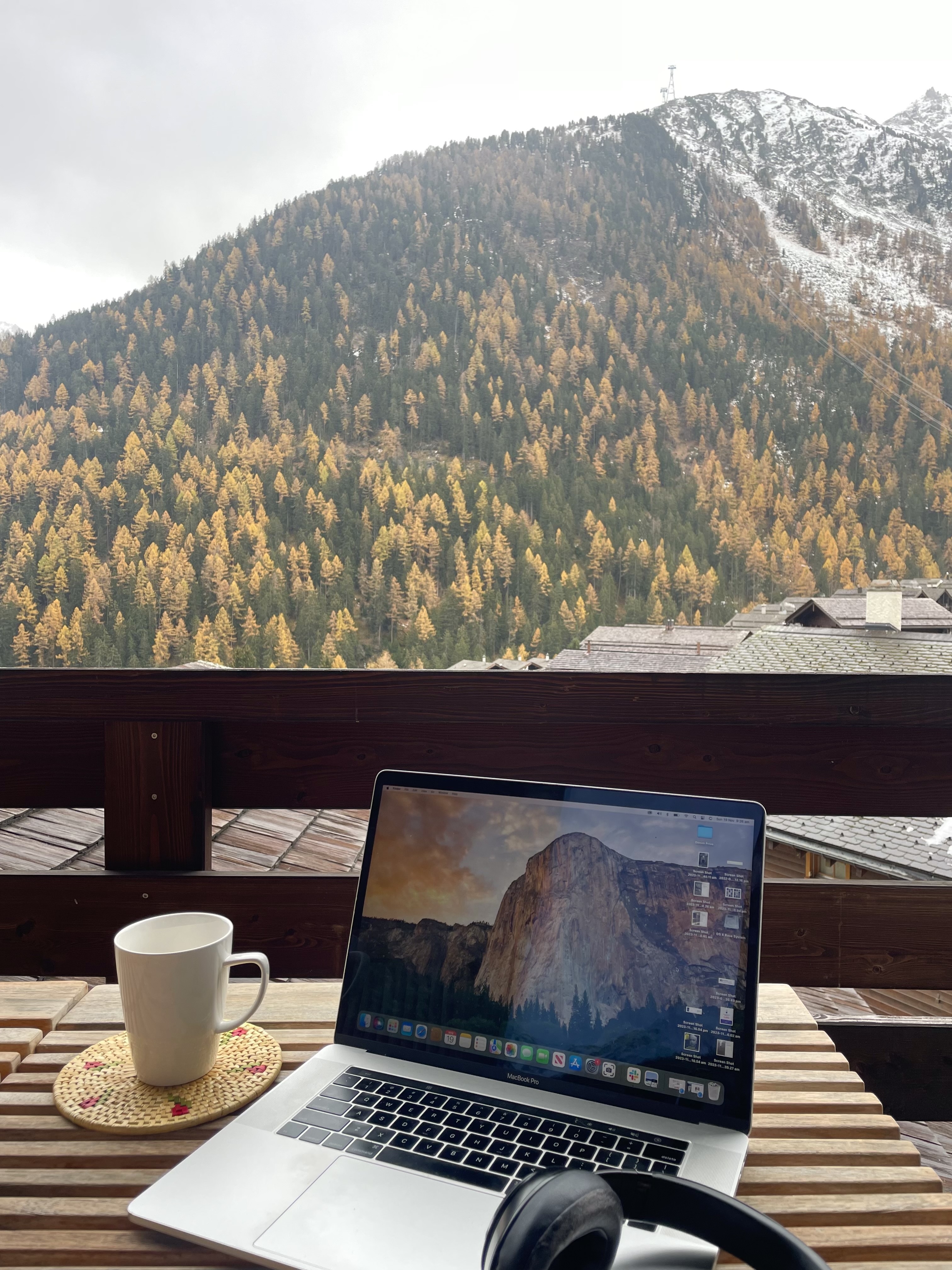 A laptop on a table in front of green mountains