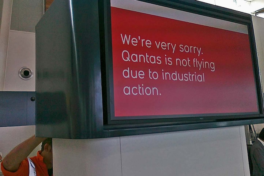 A Qantas worker adjusts a sign at Adelaide Airport to advise of more flight cancellations, October 31 2011. (ABC: Spence Denny)
