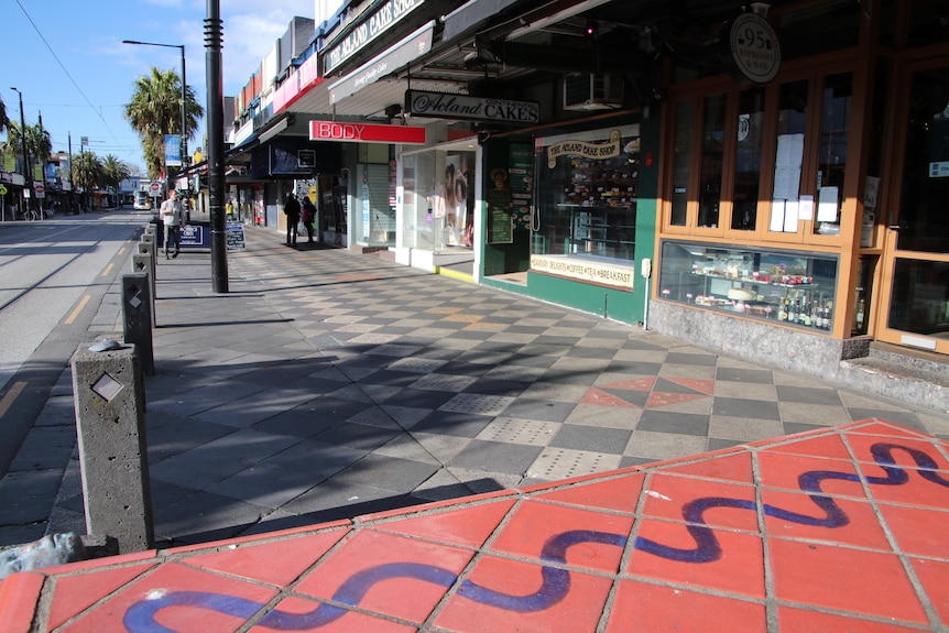 A largely deserted Acland Street, with the closed cake shop and tram tracks in view.