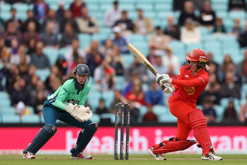 Georgia Redmayne plays a sweep shot as a wicket keeper watches on