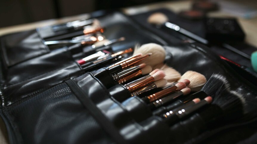 A close up shot of a leather case containing a series of different size and colour makeup brushes