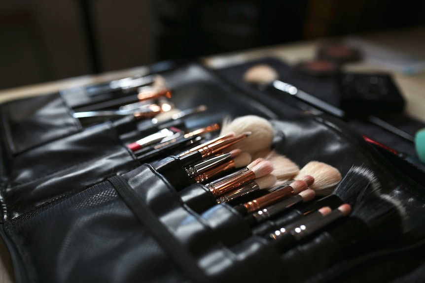 A close up shot of a leather case containing a series of different size and colour makeup brushes