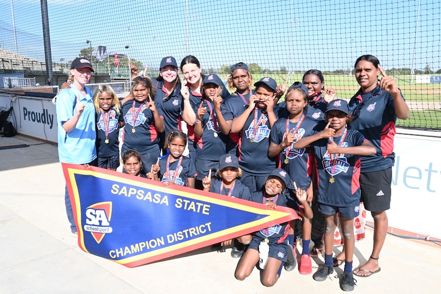 A team of junior softballers from SA's APY Lands wear medals following their tournament victory.