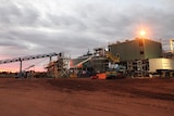 A mining plant surrounded by red dirt, with a grey sky above.