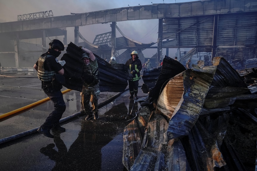 Rescuers and service members work at a site of a shopping mall hit by a Russian missile