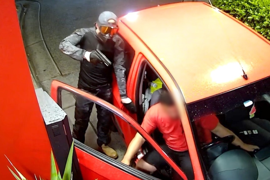 A gunman in a ski mask holds a gun to a driver's head in a drive-thru