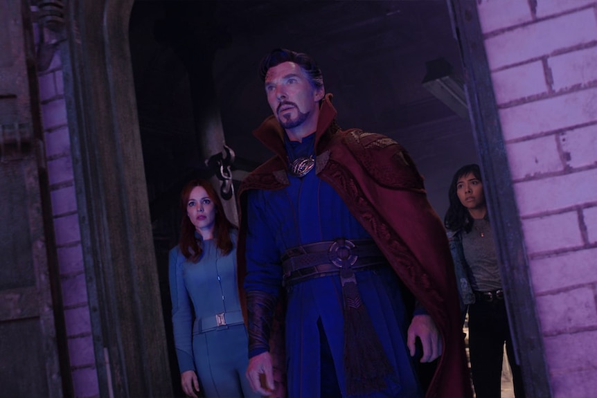 Three people in a doorway looking worried, in a scene from a movie.
