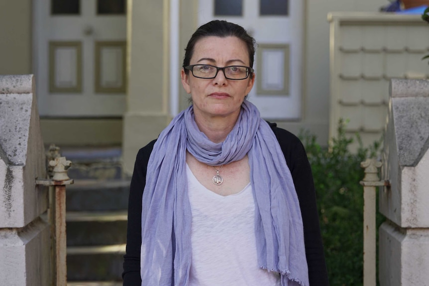 Bev stands in front of her house