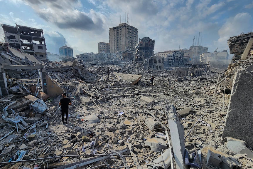 One man stands in the middle of endless rubble, with a few buildings still standing in the background