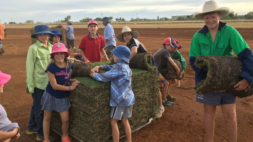 Kids help lay a pallet of turf at the Rolleston oval