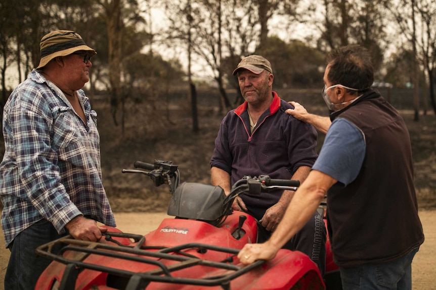 A farmer Steve Shipten with soot on his face is consoled by fellow farmers