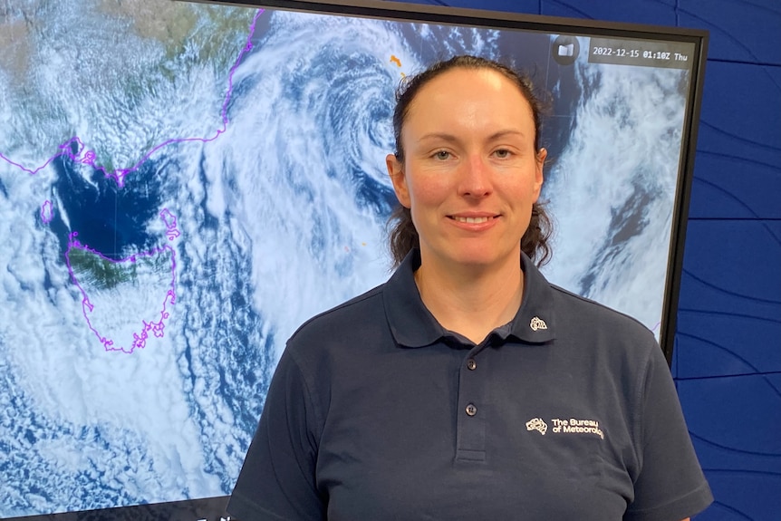 A woman wearing a collared blue shirt stands in front of a cloud map.