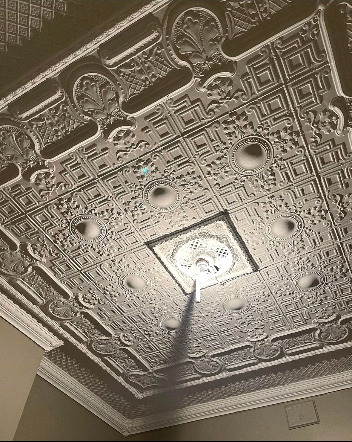 A ceiling with intricate raised designs surrounding the central light