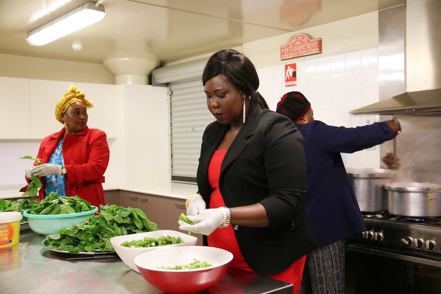 Ayuen Autiak and Alwal Madut prepare ingredients for a large batch of "kombo" in a kitchen.