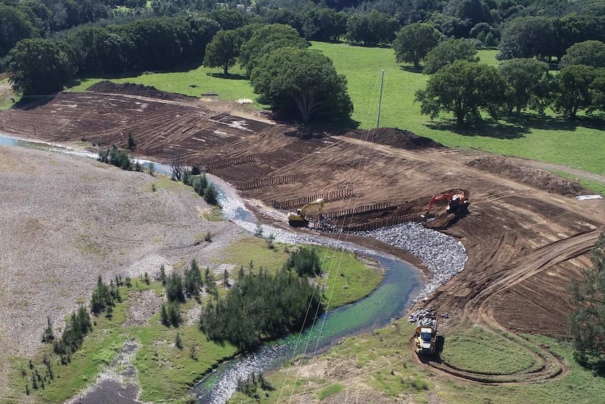 Earthmovers working to repair the eroded bank and put in pile fields.