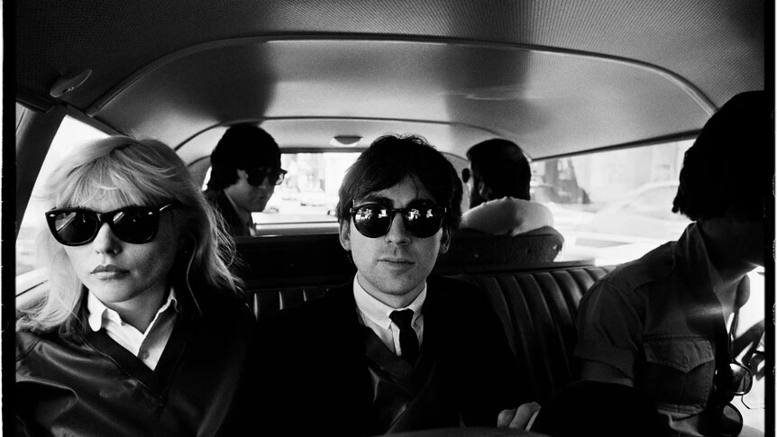 black and white photo of Chris Stein and Debbie Harry wearing sunglasses in a car