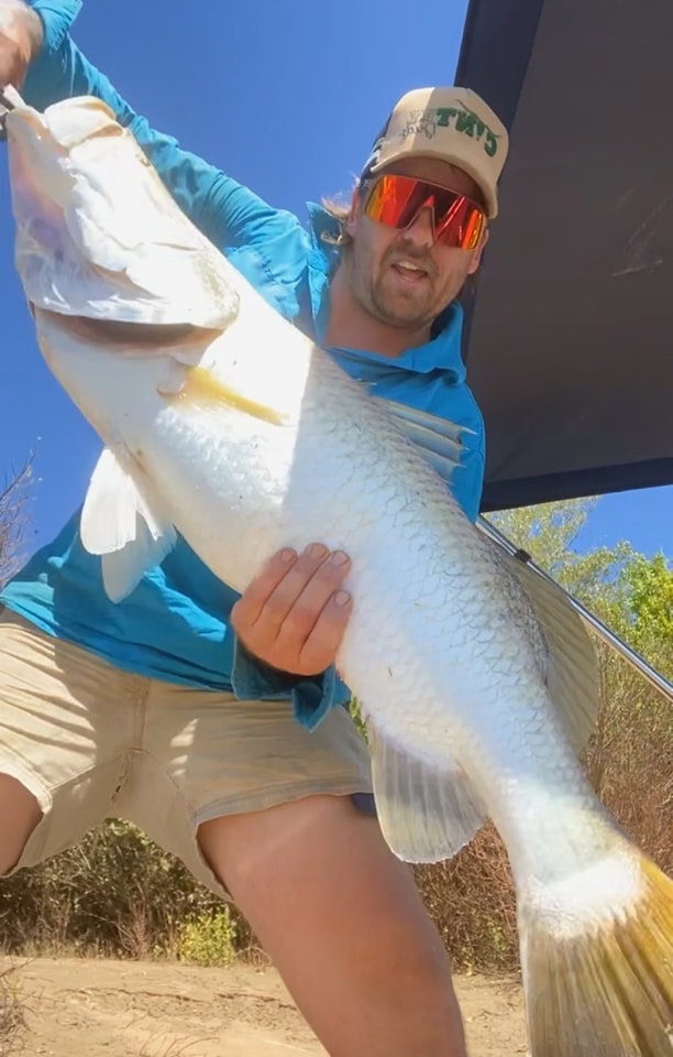 A capped man holds a massive white-bellied fish