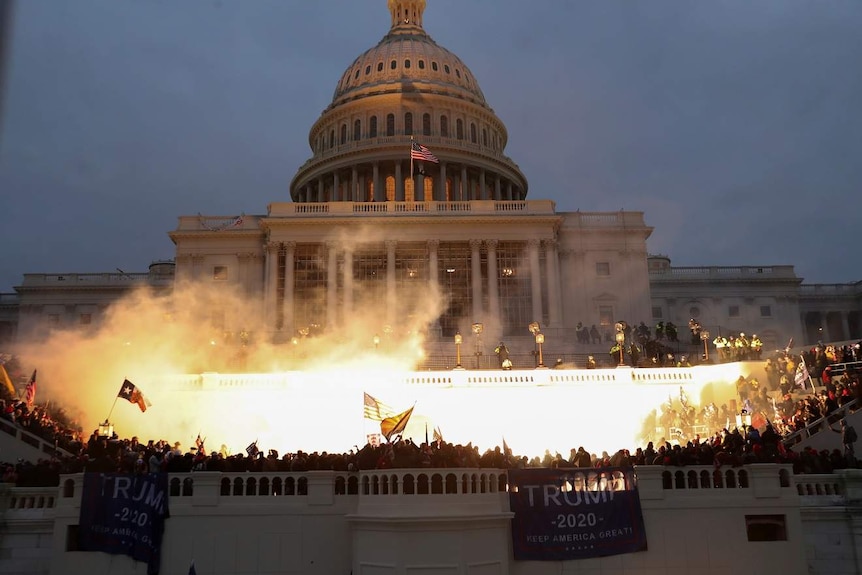 Un'esplosione causata da munizioni della polizia davanti al Campidoglio degli Stati Uniti durante una rivolta dei sostenitori di Trump.